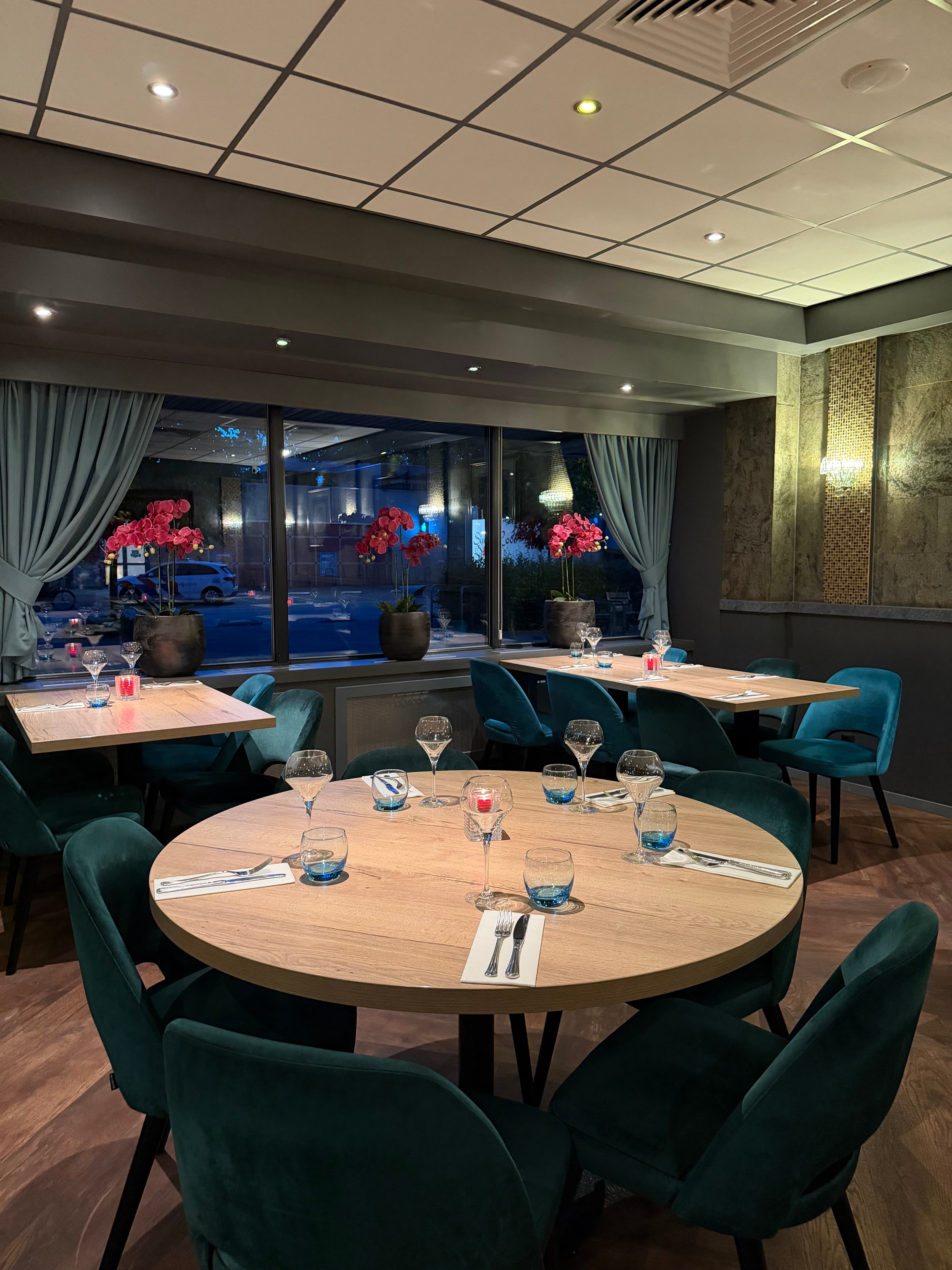 Een ronde tafel gedekt voor zes personen, met de ramen aan het plein op de achtergrond